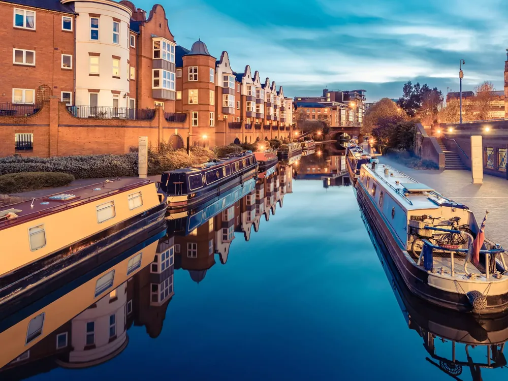 Birmingham canal at dusk with narrowboats and lit brick buildings