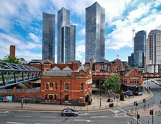 Manchester skyline with Deansgate Square towers and a red-brick railway building