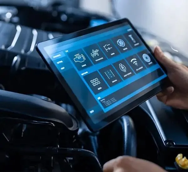 Technician using a diagnostics tablet on a car engine