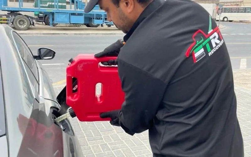 Technician pouring fuel from a red can into a car